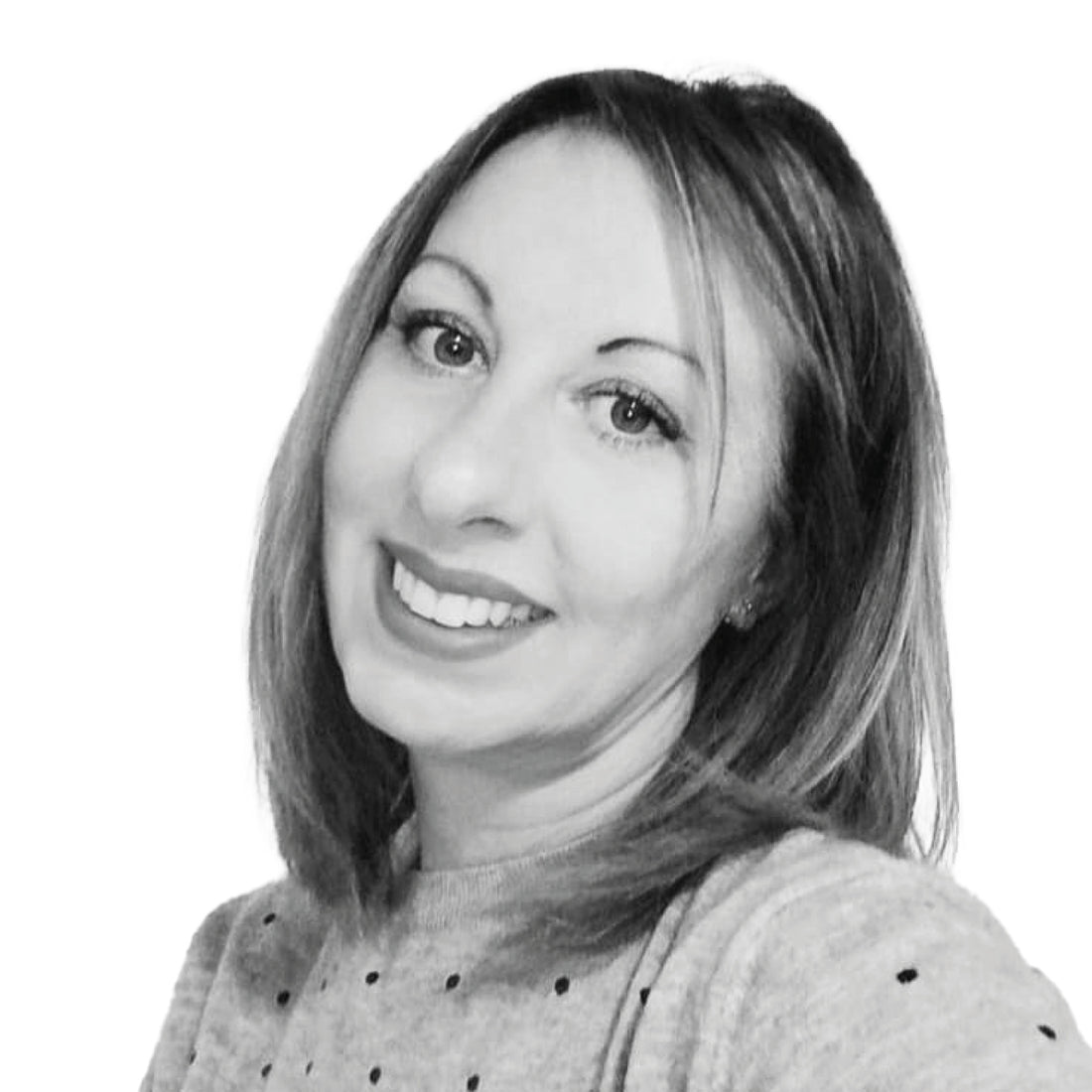 Lächelnde Frau mit schulterlangem Haar, die einen hellen Pullover trägt, fotografiert vor einem weißen Hintergrund.