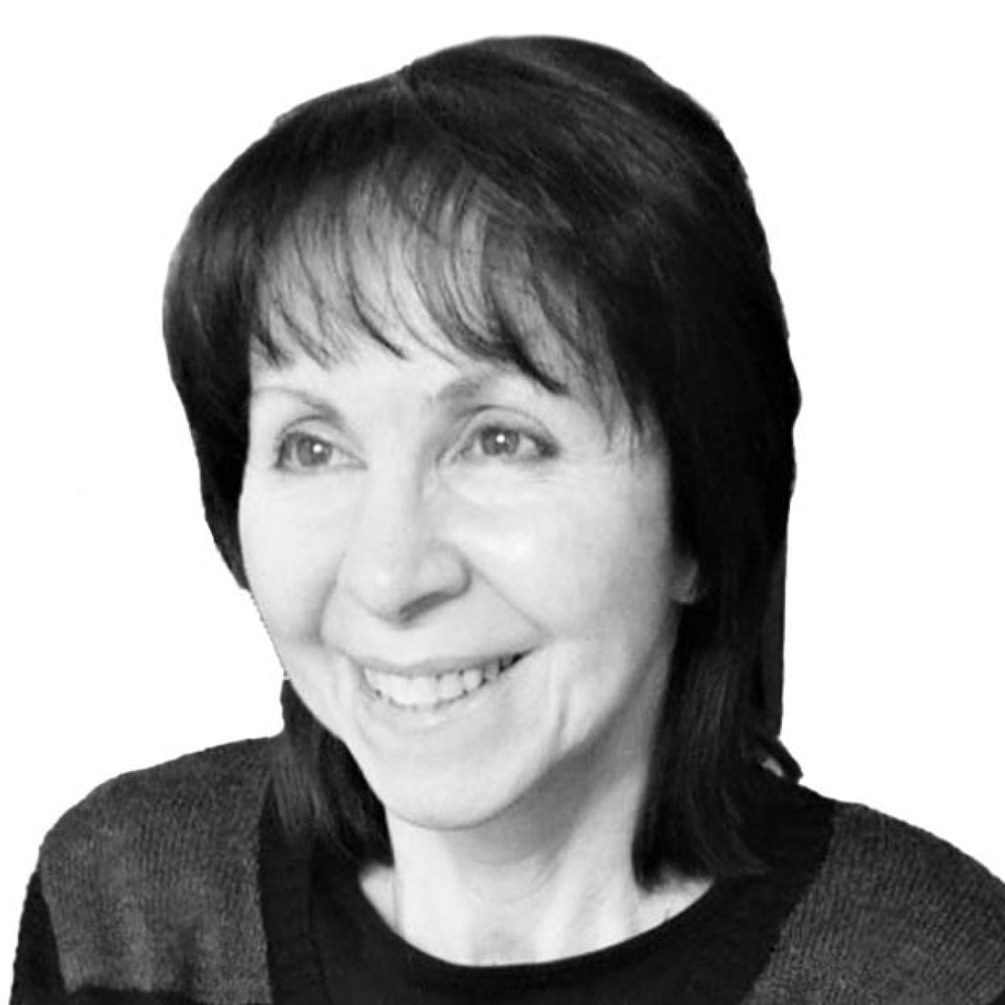 Lächelnde Frau mit kurzen dunklen Haaren und Pony, die einen dunklen Pullover trägt, vor einem weißen Hintergrund.