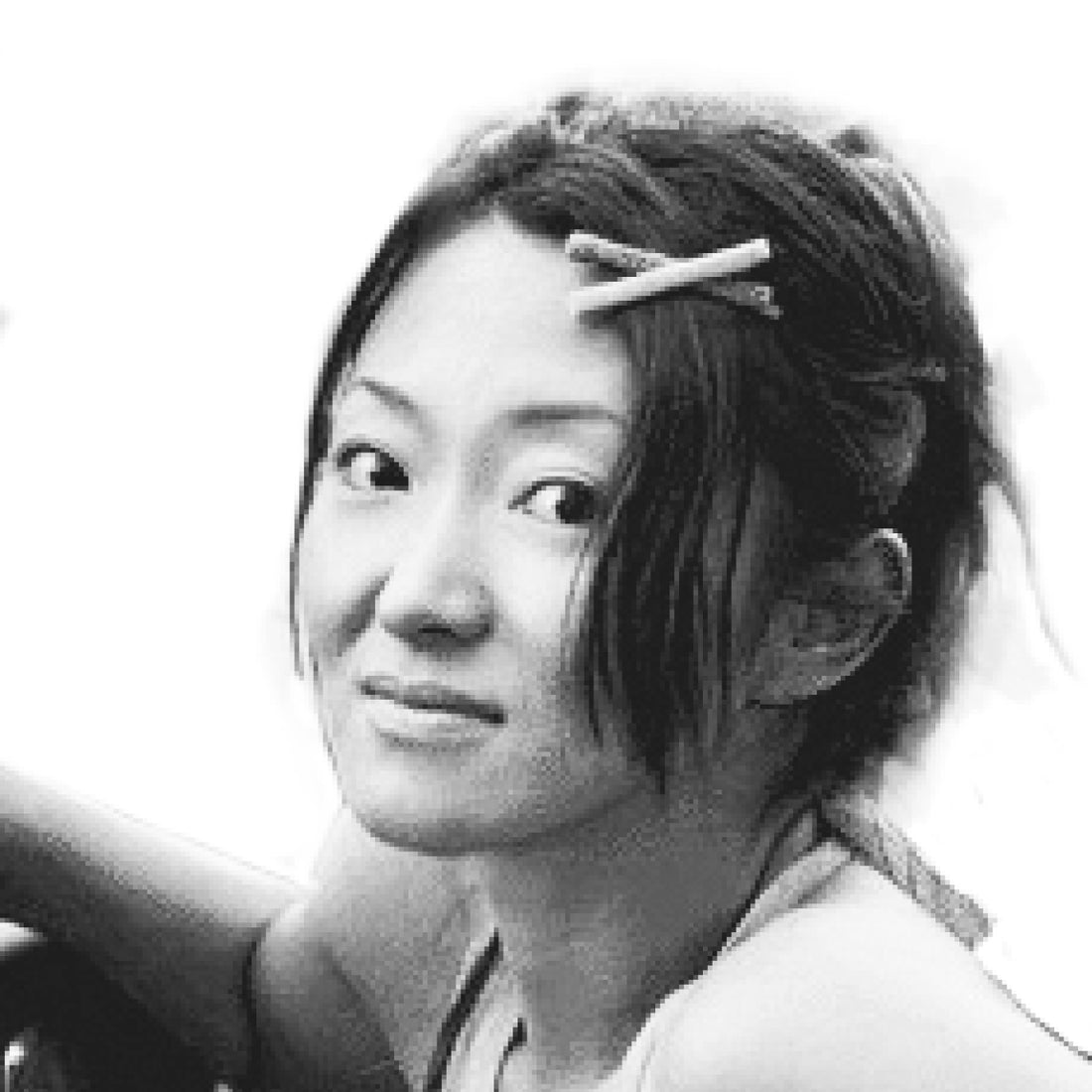 Eine Frau mit einer Haarspange lächelt leicht und schaut in die Kamera; der Hintergrund ist weiß.