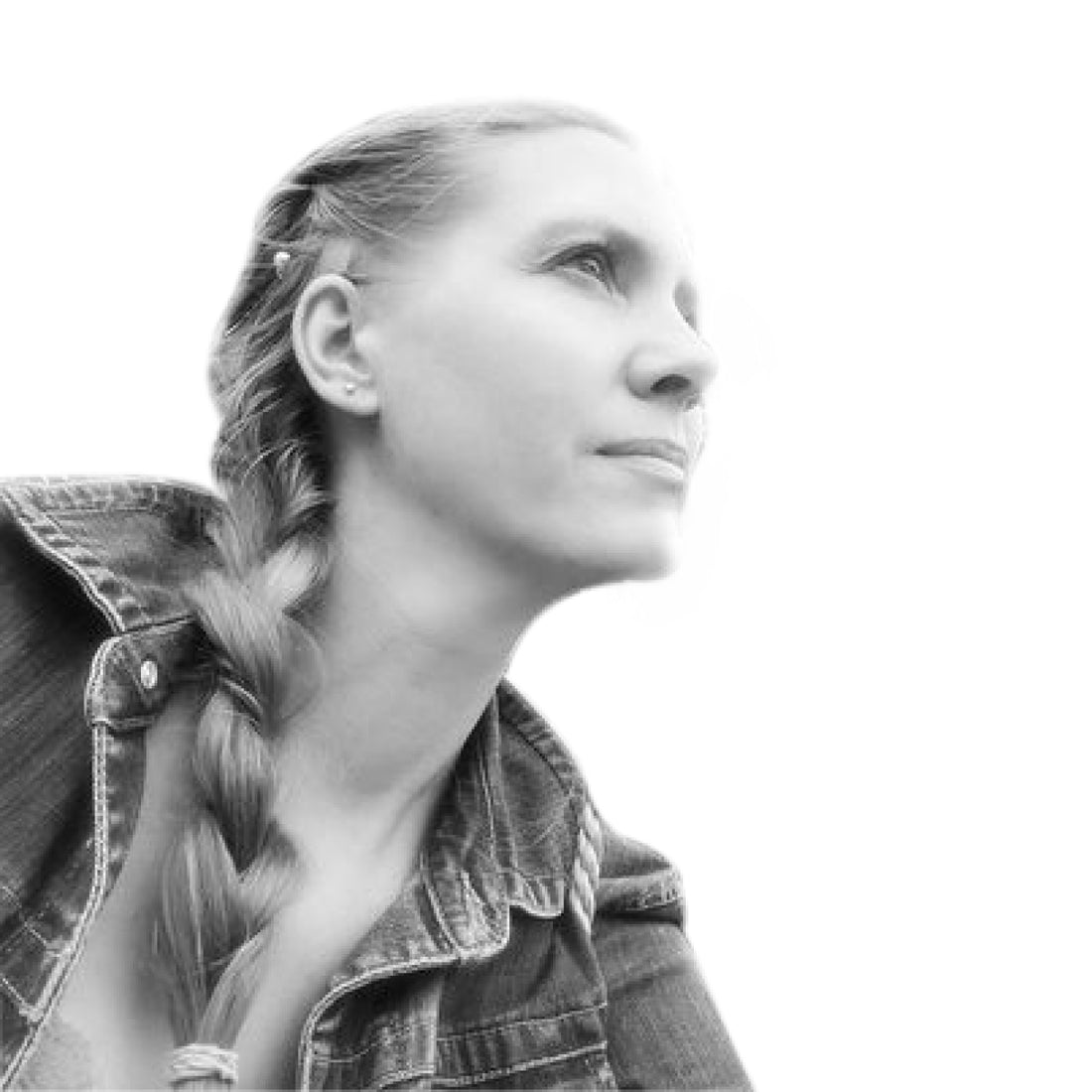 Schwarz-Weiß-Foto einer Frau mit Zopf, die eine Jeansjacke trägt und nachdenklich nach oben schaut.