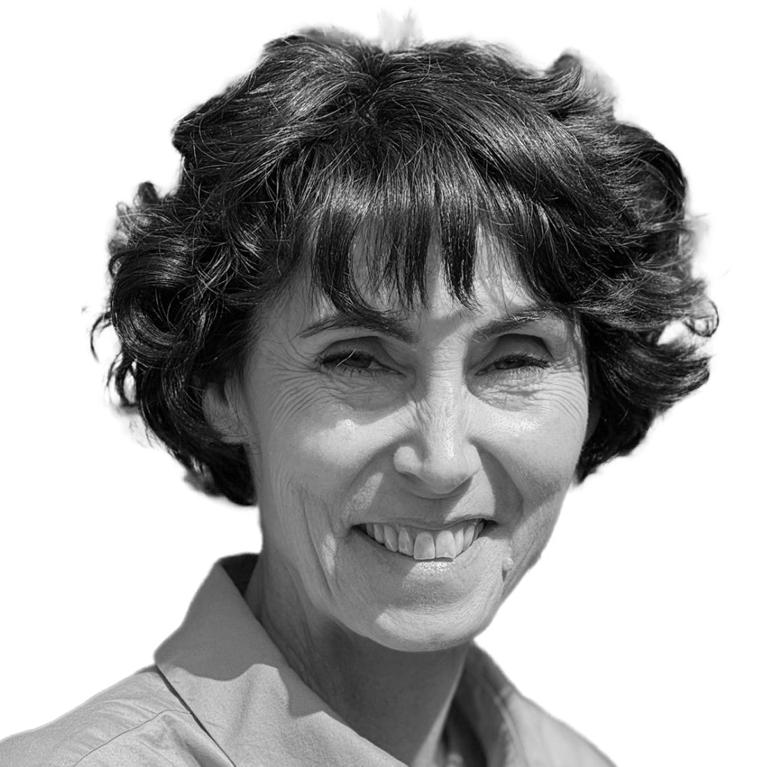 Lächelnde Frau mit kurzen, lockigen dunklen Haaren, die ein Hemd mit Kragen trägt, auf weißem Hintergrund.