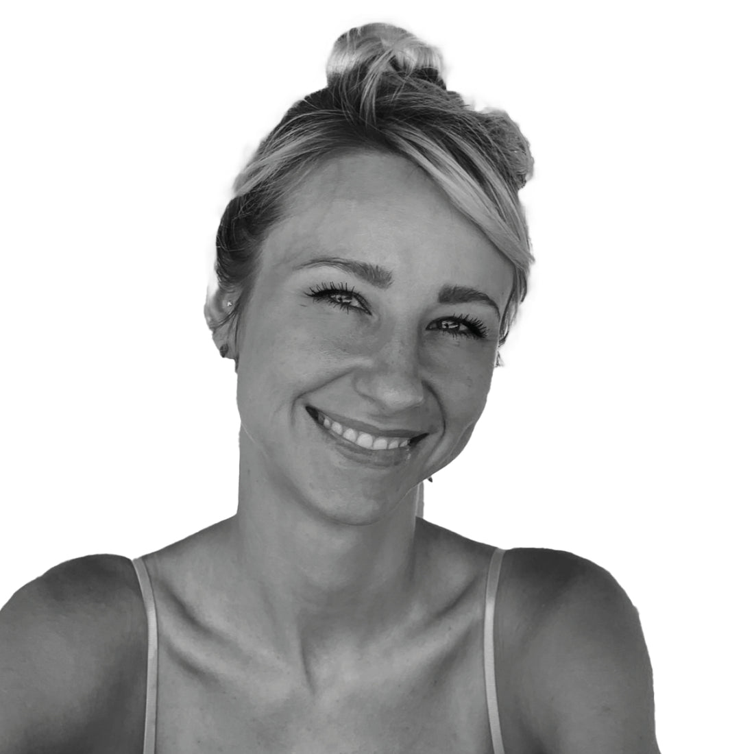 Lächelnde Frau mit Haaren in einem unordentlichen Dutt, die ein Tanktop trägt, vor einem schlichten weißen Hintergrund.