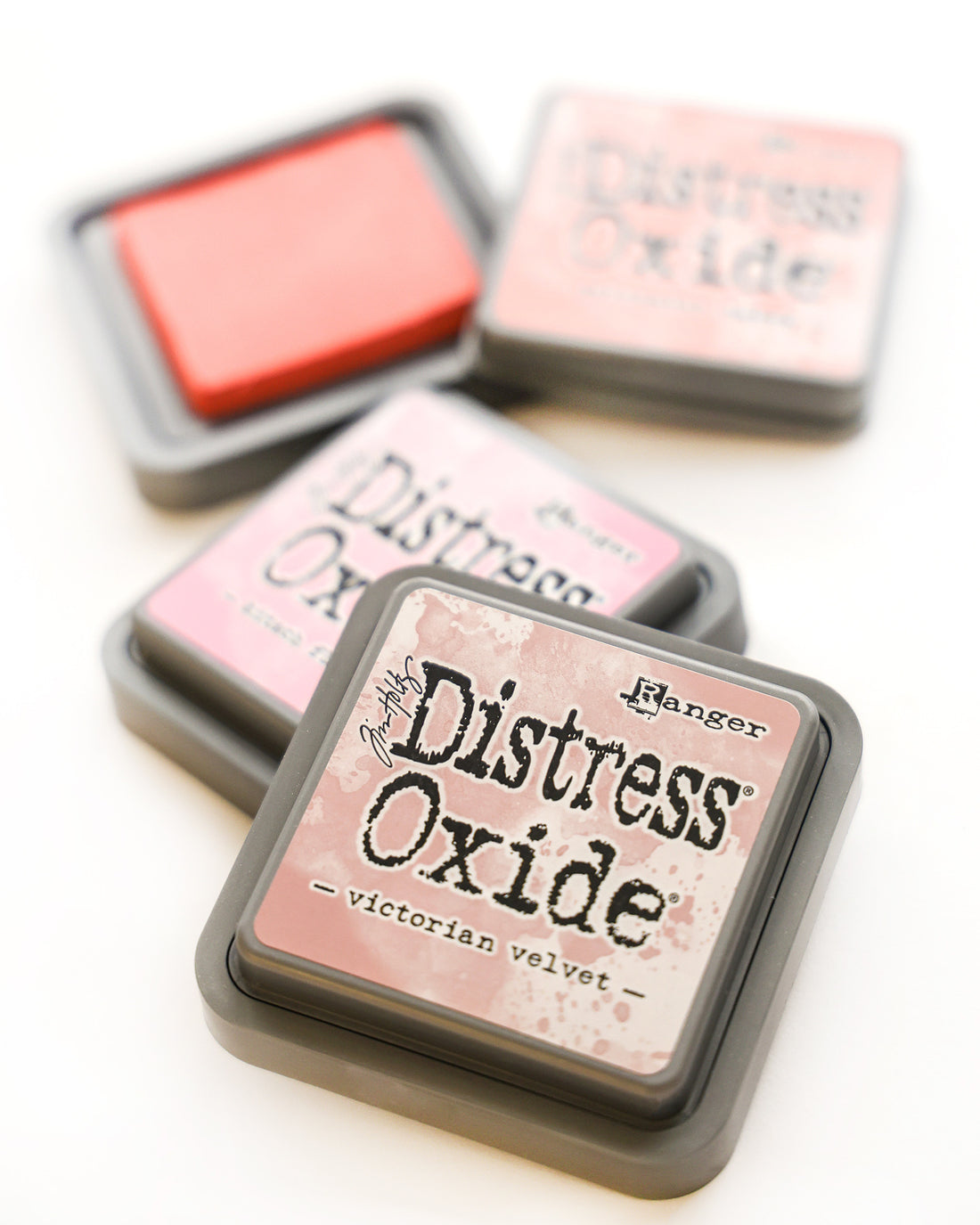 Vier Stempelkissen mit der Aufschrift Distress Oxide, wobei das vordere mit Victorian Velvet in Rosatönen beschriftet ist.