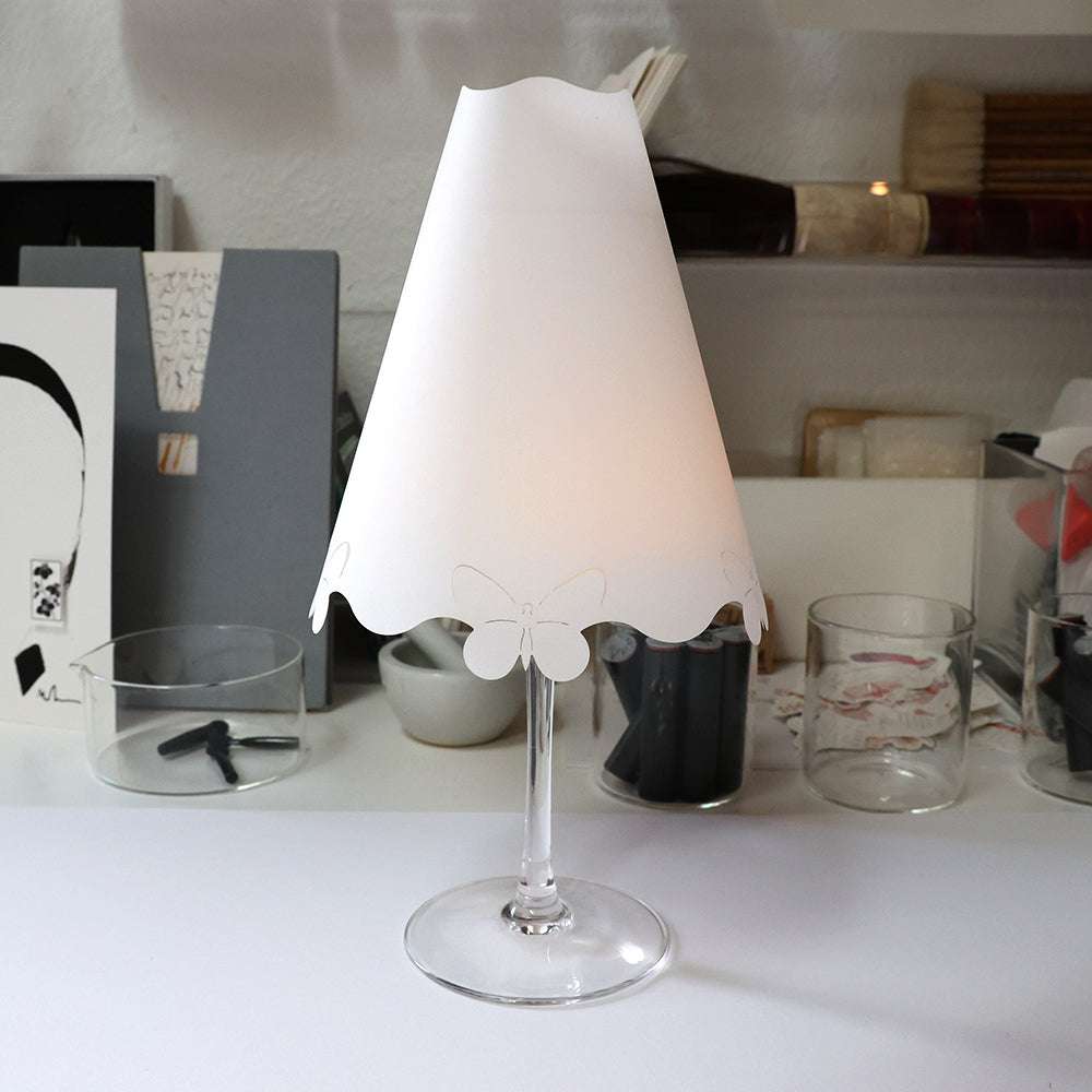 Dieses Weinglas von Alexandra Renke verfügt über einen weißen Lampenschirm in Form eines Schmetterlings. Es eignet sich perfekt als dekorative Tischleuchte oder für eine einzigartige Dekoration auf Ihrem Schreibtisch.