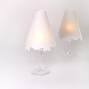 Zwei Weingläser mit sanft leuchtenden weißen Alexandra Renke Transparentpapier-Lampenschirmen auf schlichtem weißen Hintergrund - perfekt als stilvolle Tischdekoration.