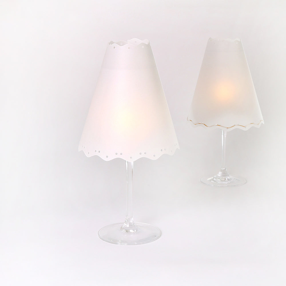 Zwei Weingläser mit weißen Papierschirmen von Alexandra Renke leuchten sanft - eine schicke DIY Lampenschirme Tischleuchte, perfekt als elegante Tischdekoration oder einzigartige Tischdeko.
