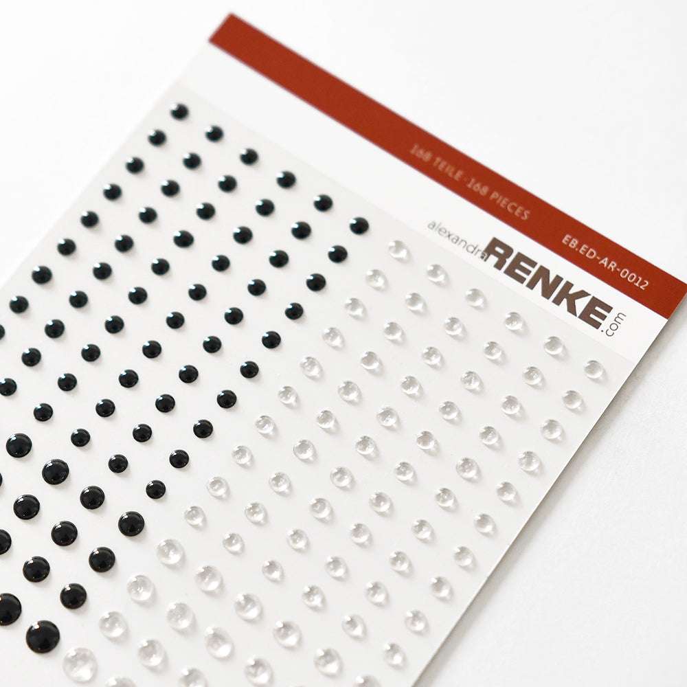 Ein Bogen Alexandra Renke schwarzer und klarer Klebe-Emaillepunkte mit Tropfeneffekt, ideal für die Kartengestaltung, sauber in Reihen auf weißem Hintergrund angeordnet.