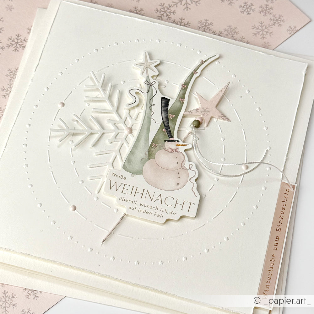 Handgemachte Weihnachtskarte auf weißem Papier mit Schneemann, Bäumen, Sternen und Schneeflocken, verziert mit dem Prägefolder Alexandra Renke Muster Kreise Sternenfreude und einem deutschen Weihnachtsgruß.