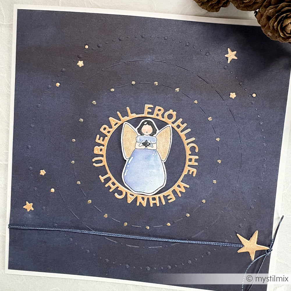 Handgemachte Karte von Alexandra Renke mit einem blauen Engel in der Mitte, deutschem Text und goldenen Sternen auf dunklem Hintergrund, hergestellt mit dem Prägefolder Muster Kreise Sternenfreude für zusätzliche Textur und Charme.