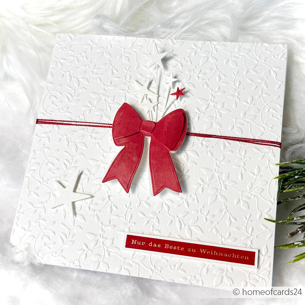 Weiße Weihnachtskarte von Alexandra Renke, gestaltet mit einem Prägefolder, mit einer roten Schleife, Sternen und dem Spruch "Nur das Beste zu Weihnachten".