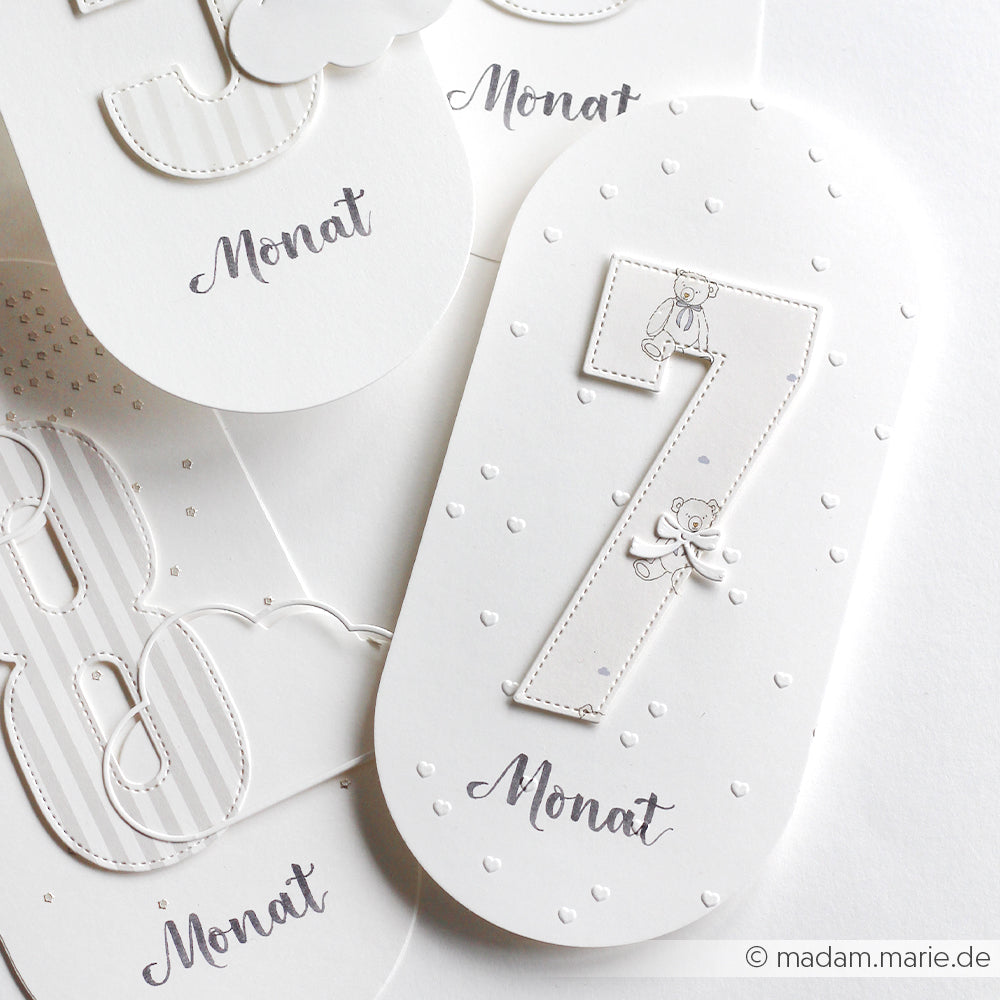 Die weißen Karten von Alexandra Renke wurden mit einem Prägefolder erstellt und zeigen die geprägten Zahlen 7, 8 und 9 mit dem Wort "Monat" in Schreibschrift unter jeder Zahl.