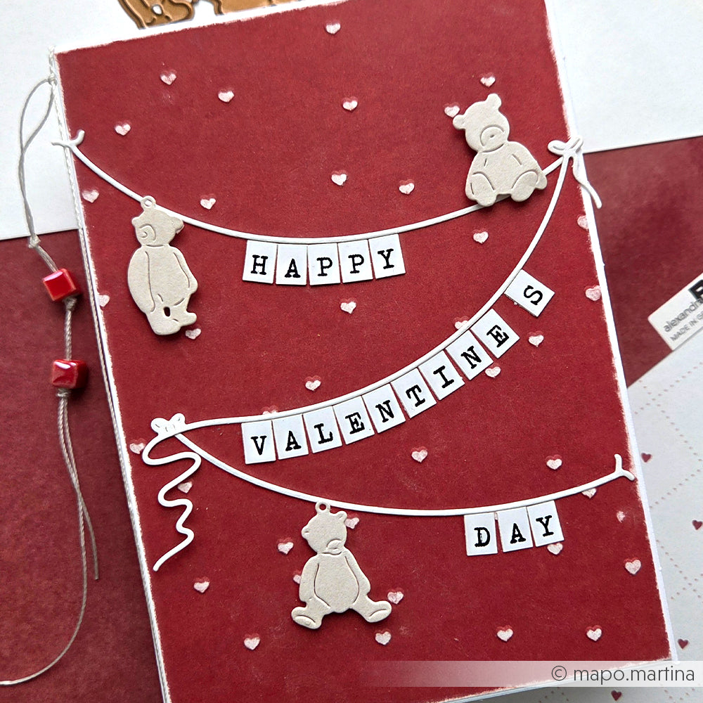Handgefertigte Valentinskarte von Alexandra Renke mit Teddybär-Ausschnitten, "Happy Valentine's Day"-Bannern und bezaubernden Herzchenregen-Akzenten, die auf einen roten, herzförmigen Hintergrund geprägt sind.