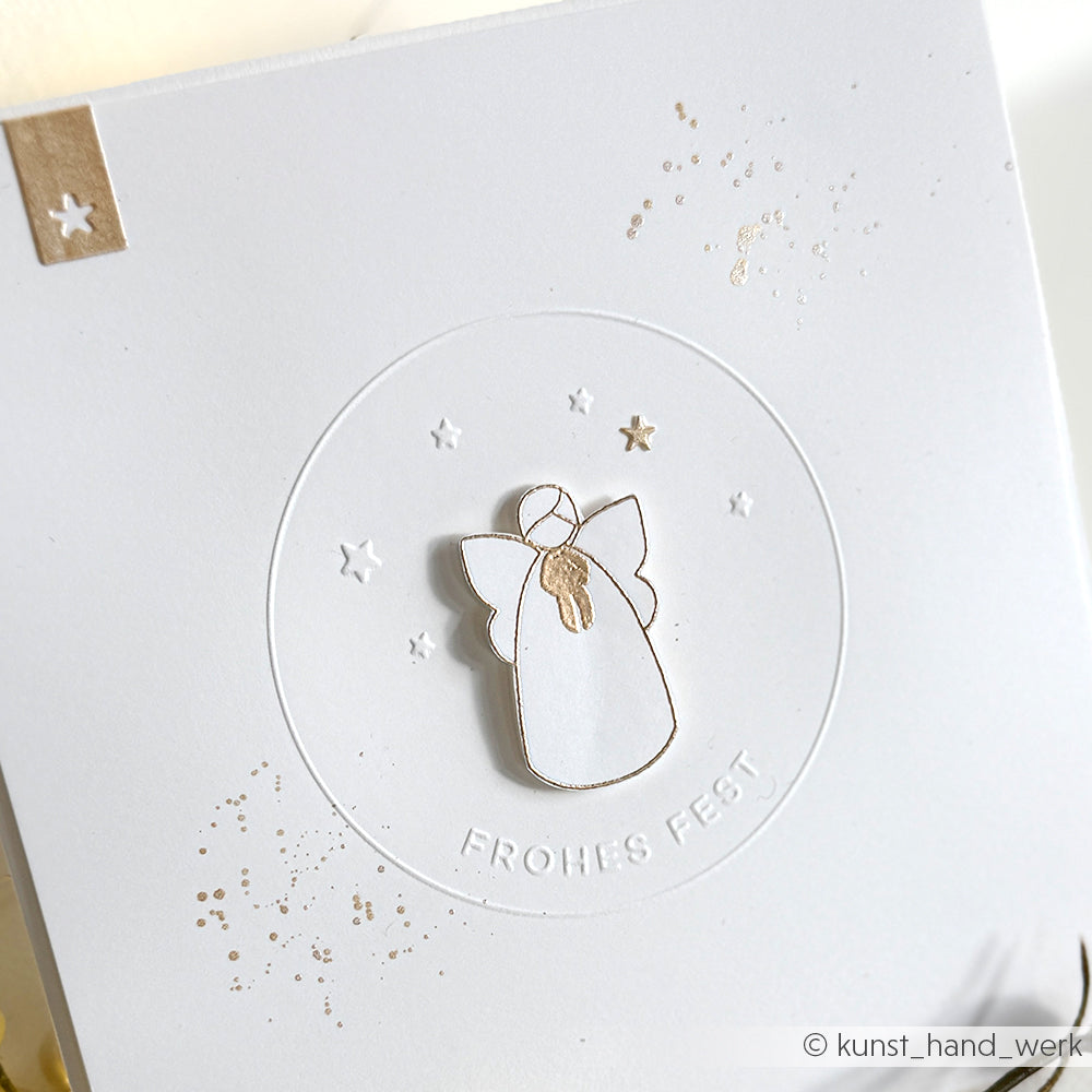 Minimalistische Karte von Alexandra Renke mit einer weißen Engelsillustration, die mit dem Cut & Emboss Folder "Frohes Fest" geprägt und mit kleinen Sternen verziert wurde.