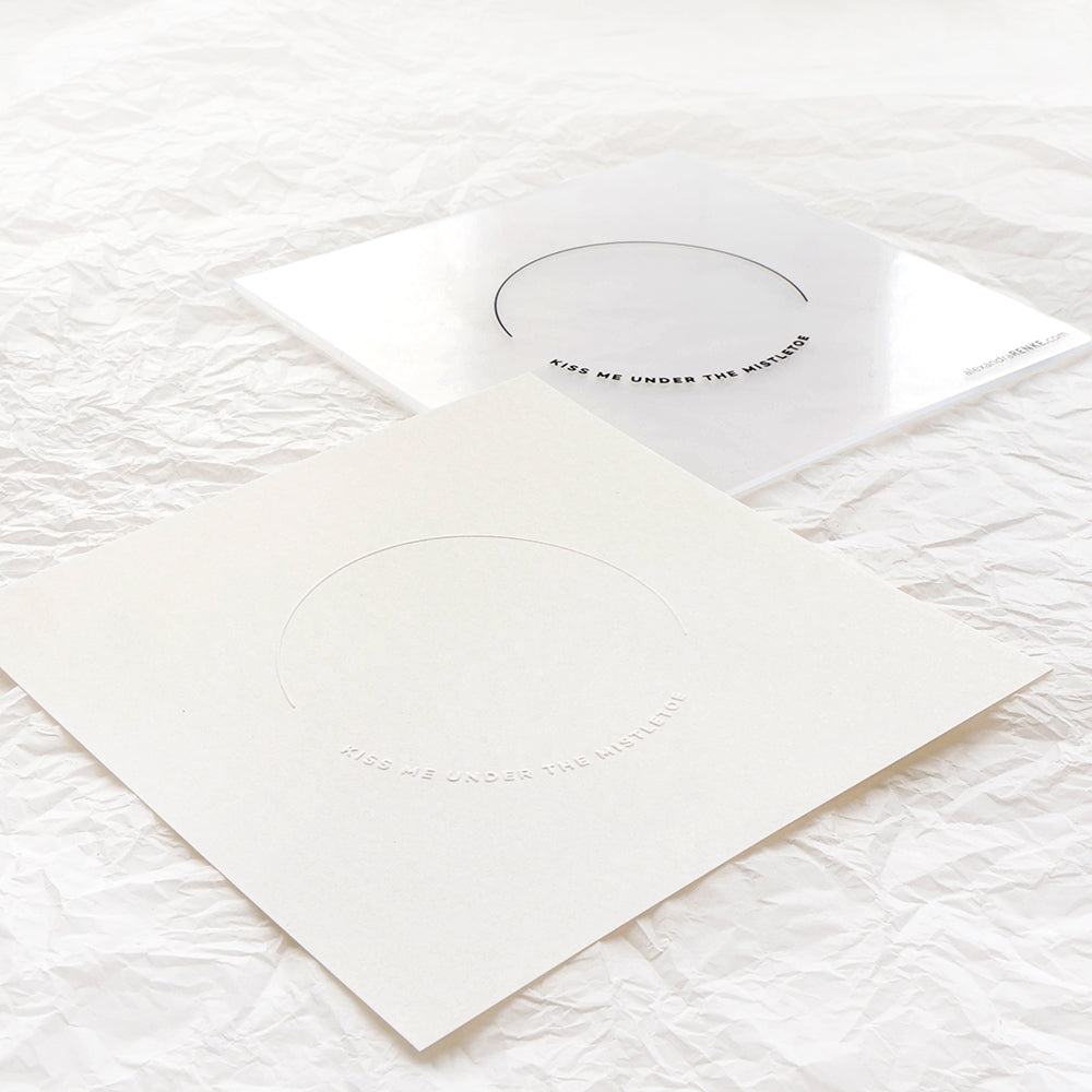 Zwei minimalistische weiße und transparente Karten mit bogenförmigen Ausschnitten, die mit einem Alexandra Renke Stanzsystem oder Prägefolder hergestellt wurden und auf zerknittertem weißem Papier präsentiert werden.