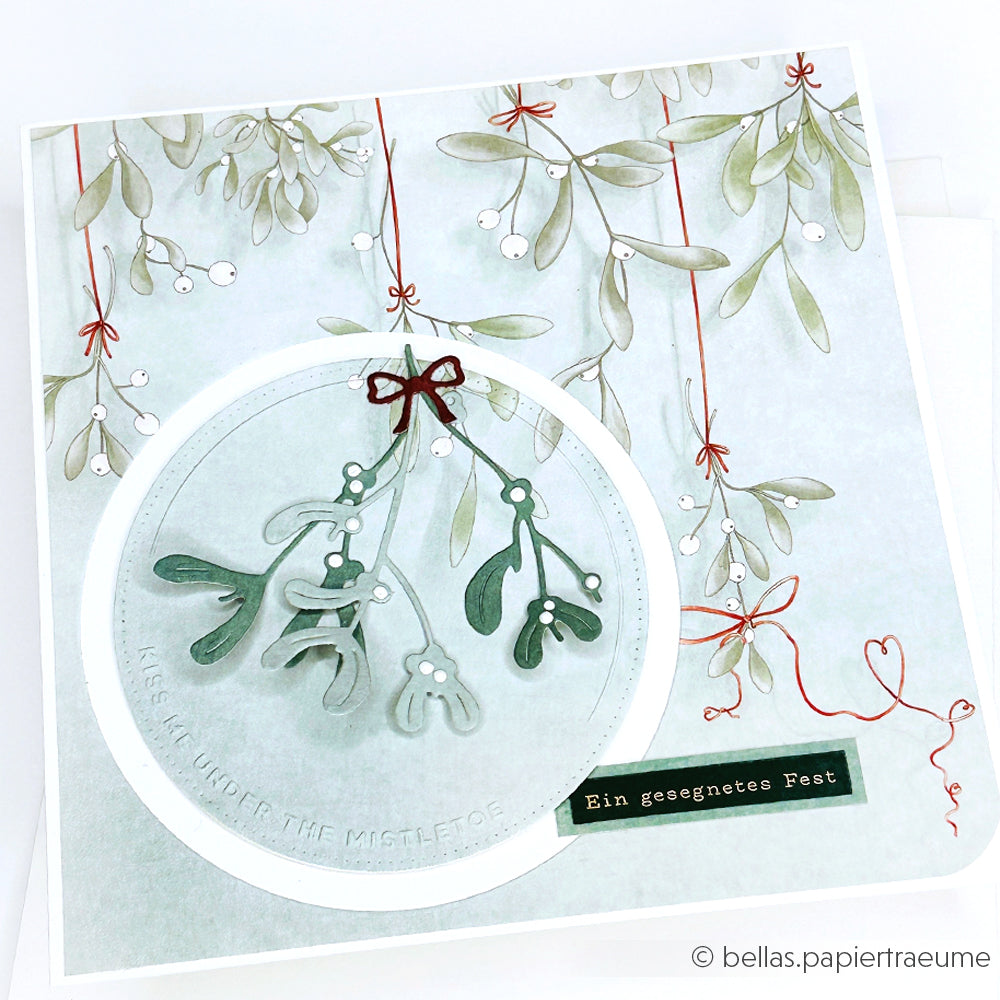 Eine festliche Karte von Alexandra Renke mit einem Mistelzweig, einer roten Schleife und "Ein gesegnetes Fest" auf Deutsch, wunderschön strukturiert mit dem Cut & Emboss Folder.