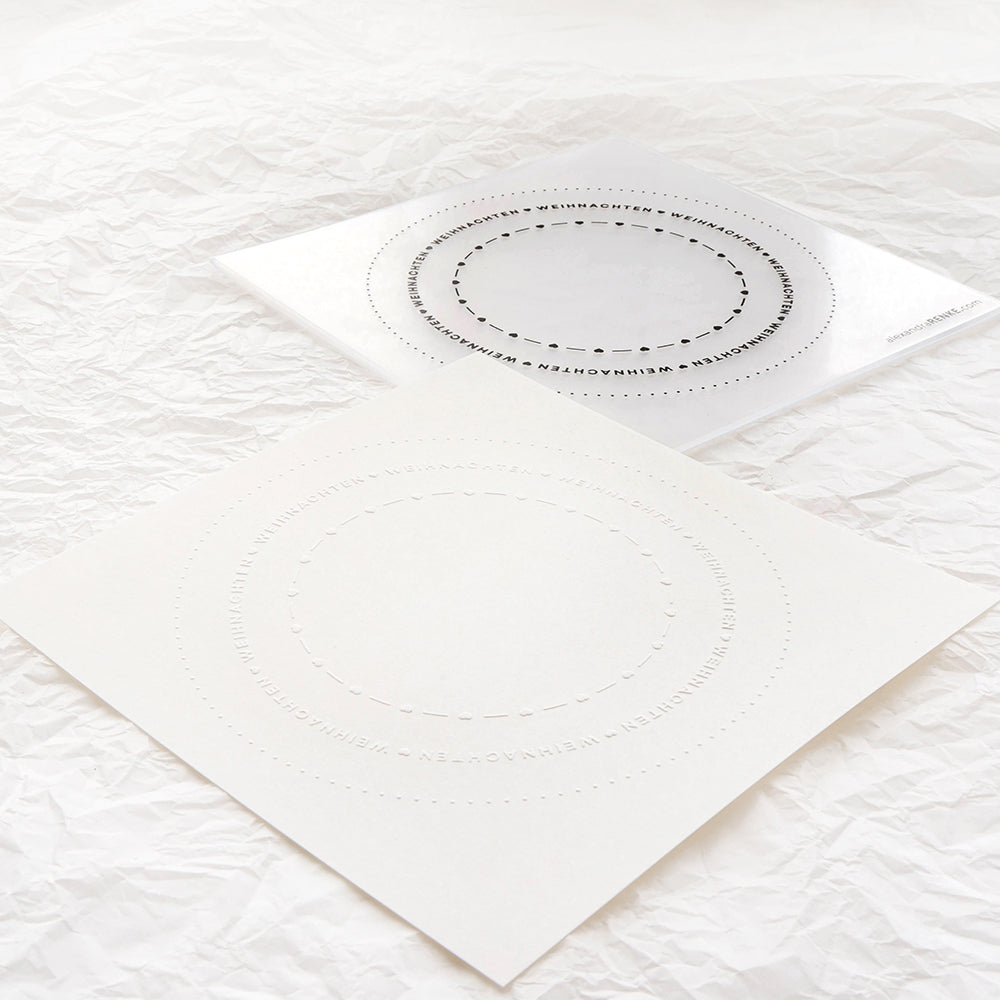 Zwei quadratische Alexandra Renke Bögen mit kreisförmig gepunkteten Linien und Text liegen auf einer zerknitterten weißen Oberfläche - ideal, um Ihre Lieblingskreationen mit Cut & Emboss Folder oder Stanzsystemen hervorzuheben.
