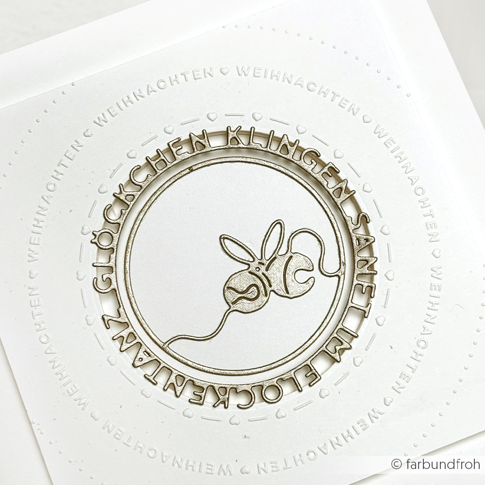 Weiße Karte von Alexandra Renke, hergestellt mit einem Embossing Folder, mit geprägtem deutschen Text und einer zentralen Linienzeichnung einer Maus, die ein Garnknäuel hält.