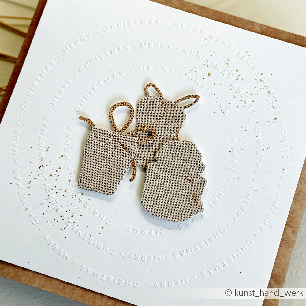 Drei strukturierte Geschenkformen mit Schleifen, hergestellt mit dem Schneide- und Prägefolder von Alexandra Renke auf weißer Karte, akzentuiert durch den runden Text "Frohe Weihnachten".