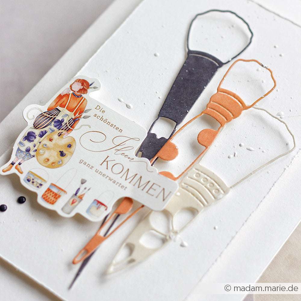 Alexandra Renke's Papertie-Projekte Ephemera und Papierausschnitte von Malwerkzeugen, kombiniert mit deutschen Texten, sind auf einem weißen, strukturierten Hintergrund zu einer skurrilen Papierelemente-Collage arrangiert.