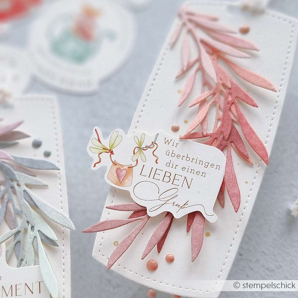 Eine handgefertigte Karte von Alexandra Renke mit pastellfarbenen Blattausschnitten, zarten Papierelementen, einer deutschen Botschaft, Perlen und illustrierten Vögeln - ideal für Papertie-Projekte oder als einzigartige Ephemera.