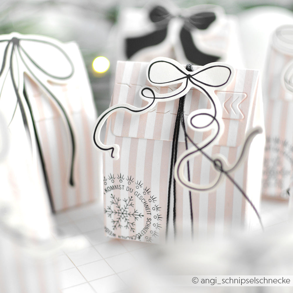 Sanft gestreifte Geschenkboxen von Alexandra Renke mit schwarzen und weißen Schleifen, Schneeflockenmotiven und eleganten Ephemera-Akzenten.