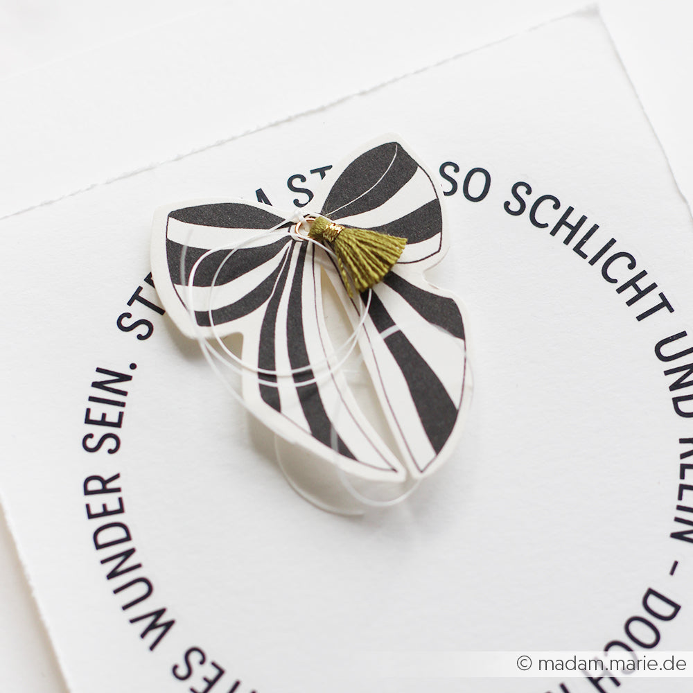 Eine schwarz-weiße Karte in Schmetterlingsform mit grüner Quaste von Alexandra Renke, gefertigt aus exquisiten Papierelementen. Ideal für Papertie-Projekte oder als einzigartige Ephemera in Ihrer Sammlung.