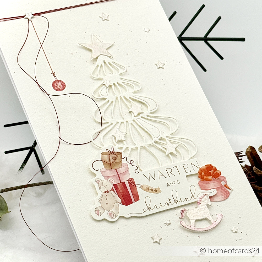 Handgefertigte Weihnachtskarte von Alexandra Renke mit weißem Baum, Geschenken, Schaukelpferd und dem Spruch "Warten aufs Christkind", verziert mit zauberhaften Papierelementen von Papertie für einen festlichen Touch.