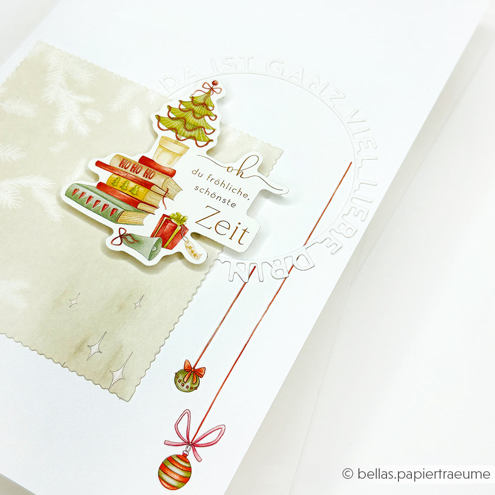 Eine handgefertigte Weihnachtskarte von Alexandra Renke mit Büchern, einem Baum, Ornamenten, deutschem Text, festlichem Dekor und charmanten Ephemera Papierelementen - ideal für Papertie-Projekte.