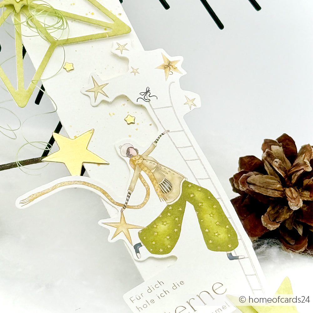 Handgemachte Karte von Alexandra Renke mit einem Sternenmotiv mit einem Mädchen, das auf eine Leiter klettert, schimmernden goldenen Sternen und einem Tannenzapfen an der Seite.