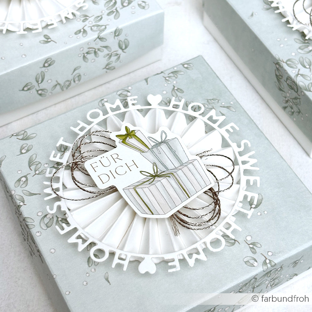 Dekorative Geschenkbox von Alexandra Renke mit "Home Sweet Home"-Schriftzug, Grünzeug und gestapelten "Für Dich"-Geschenken - ideal für Papertie-Projekte oder um Ihre kreativen Bastelarbeiten mit unverwechselbaren Ephemera und Papierelementen zu ergänzen.