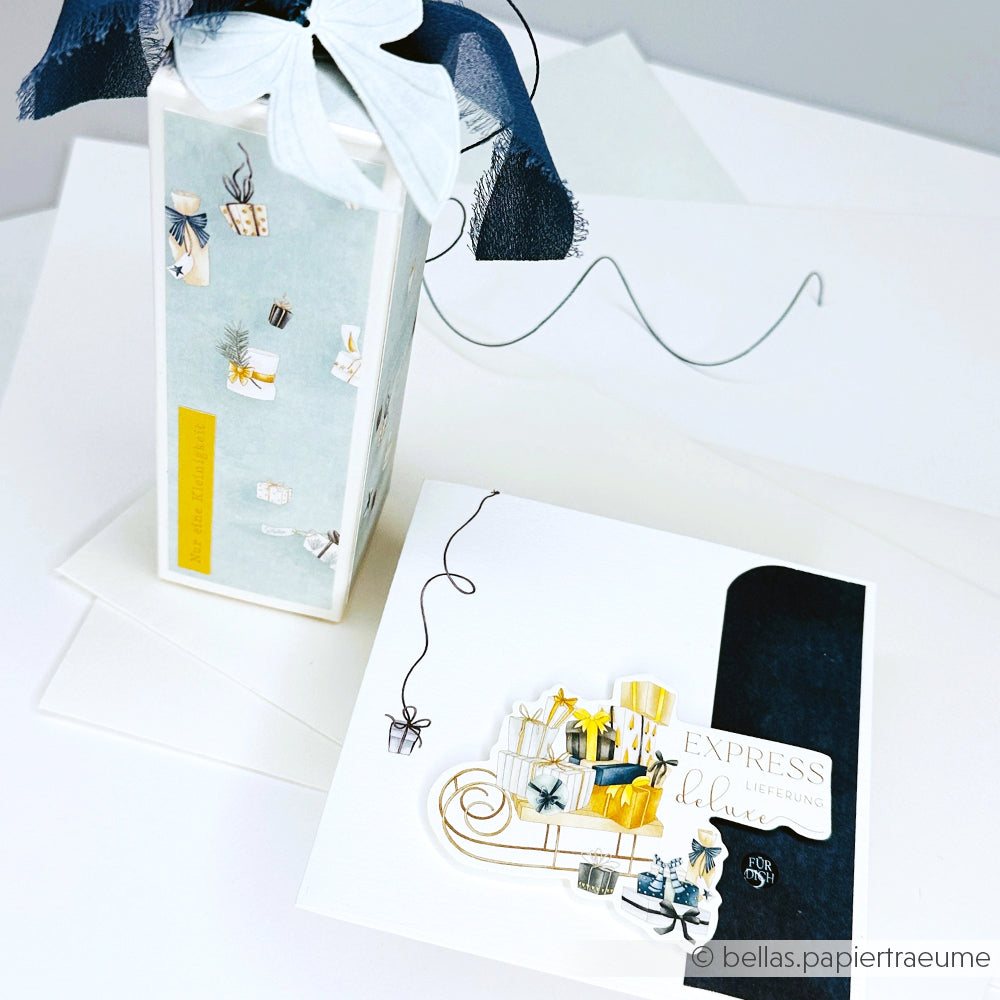 Eine verzierte Geschenkbox und eine passende Grußkarte von Alexandra Renke mit charmanten Geschenk- und Bandmotiven in Weiß, Gelb und Marineblau - die perfekten Papierelemente für Ihre nächsten Papertie-Projekte.