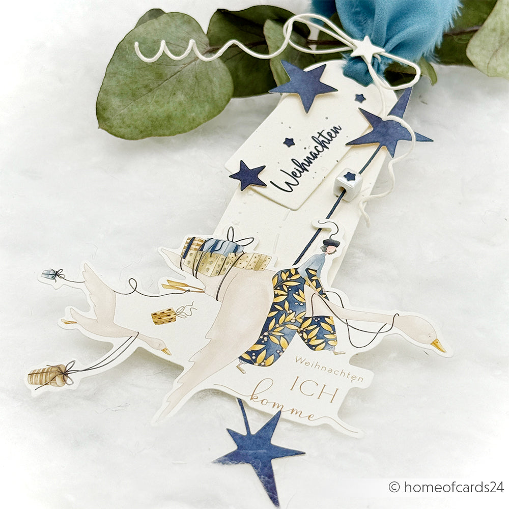 Handgefertigter Weihnachtsanhänger von Alexandra Renke mit Gänsen, Geschenken, blauen Sternen, deutschem Text und Blättern auf hellem Hintergrund - perfekt für Papertie-Projekte oder zum Hinzufügen festlicher Ephemera zu Ihren Weihnachtsbasteleien.