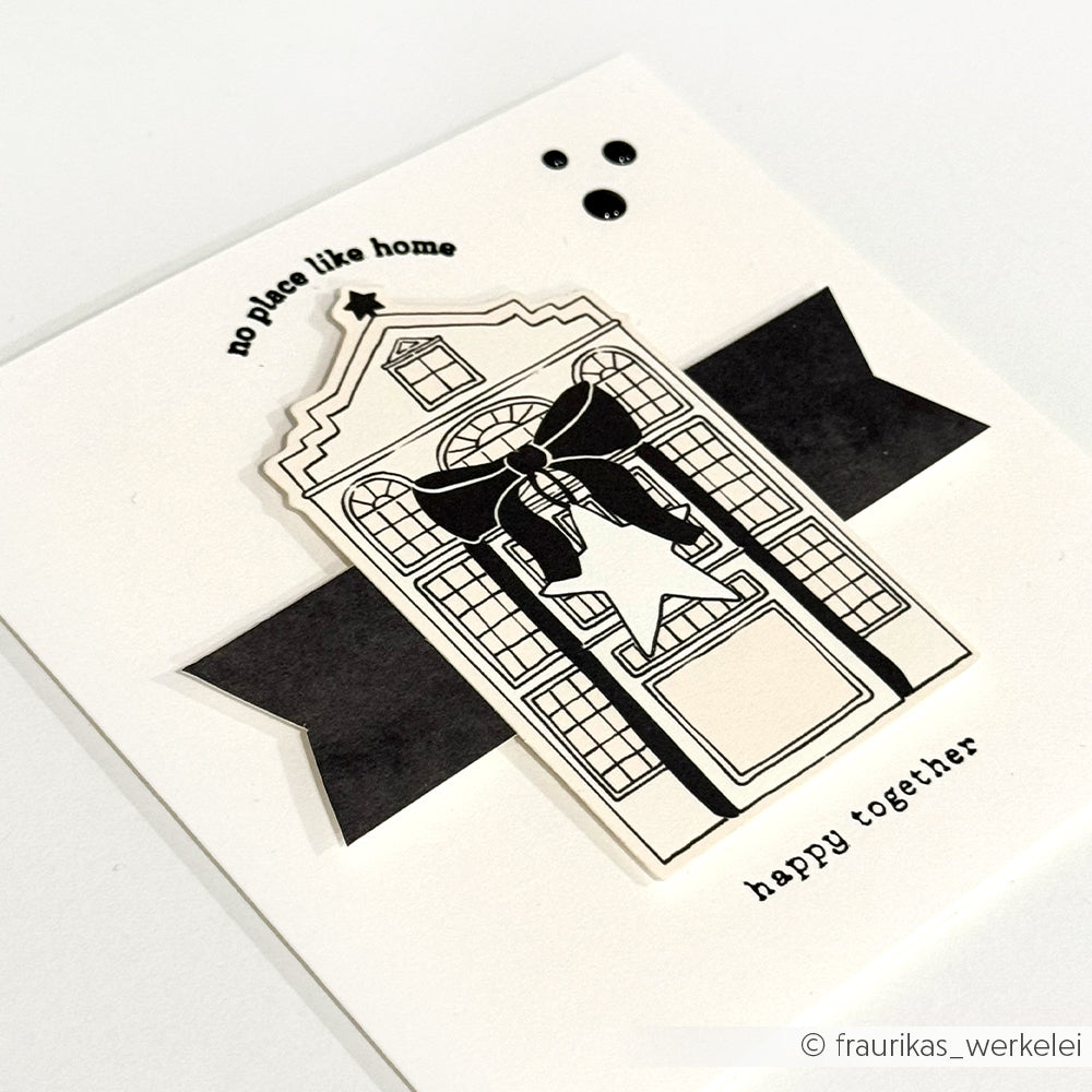Handgemachte Karte von Alexandra Renke mit Papierelementen, die ein Haus, eine Schleife und zwei Figuren zeigen. Mit den Texten "no place like home" und "happy together".