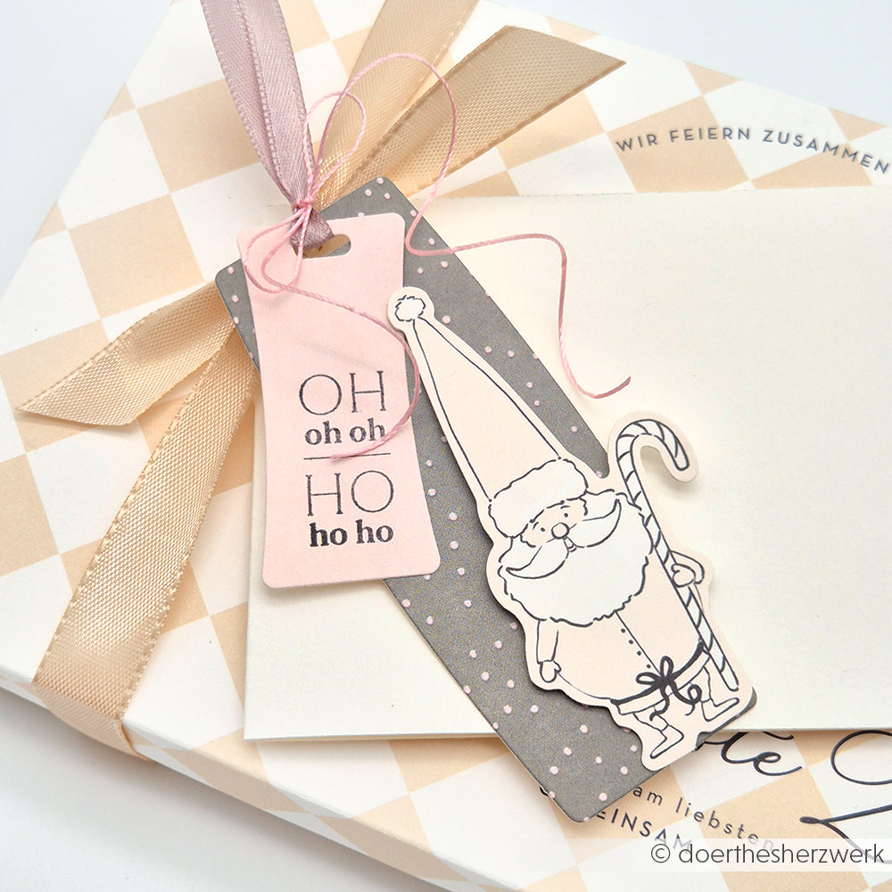 Die Geschenkanhänger von Alexandra Renke sind mit einer Weihnachtsmann-Illustration und dem Text "OH oh oh HO ho ho" versehen und mit einem rosafarbenen Band verschnürt - perfekte festliche Akzente, um Papierelemente und Ephemera zu Ihren weihnachtlichen Papertie-Projekten hinzuzufügen.