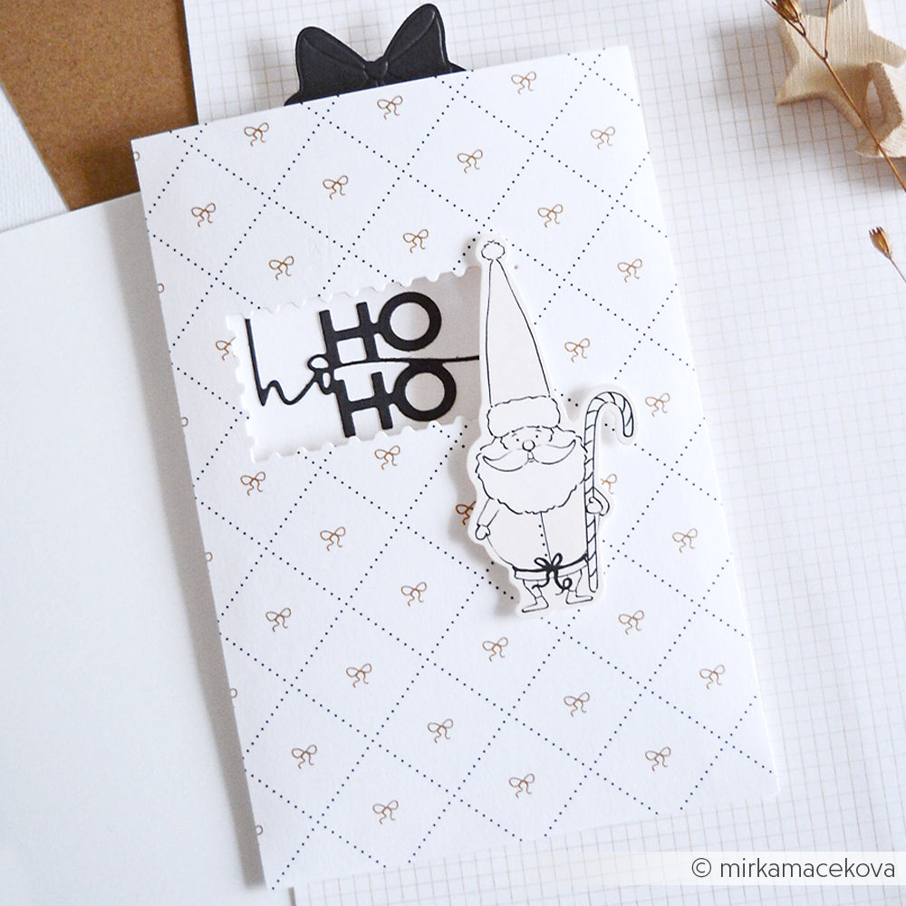 Weiße Karte mit dem Text "HO HO HO" und einem schwarz-weißen Gnom mit Zuckerstange, akzentuiert durch Alexandra Renke Papierelemente auf einem festlich gemusterten Hintergrund.