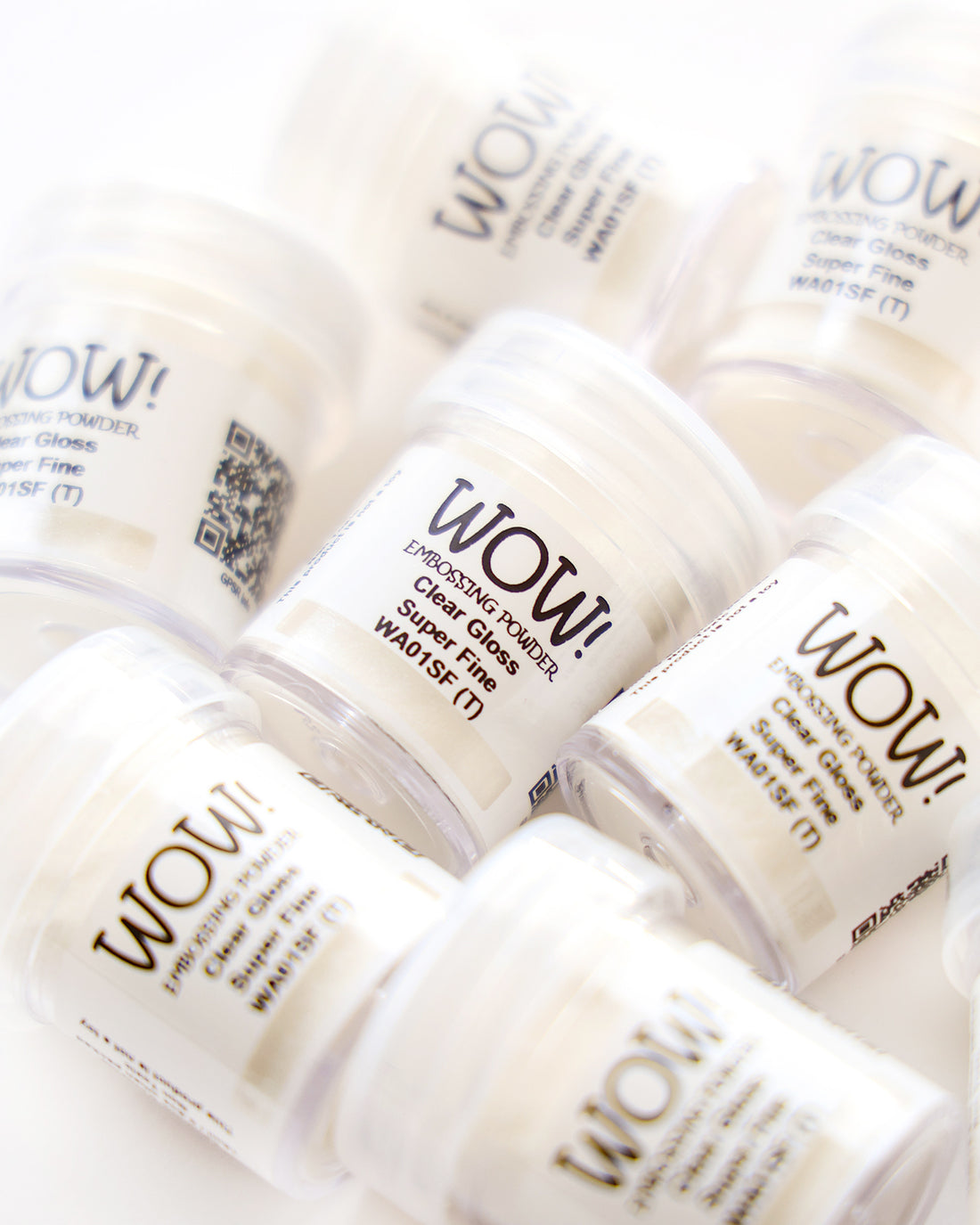Kleine Dosen mit weißem WOW! Embossingpulver auf einer weißen Fläche verstreut.