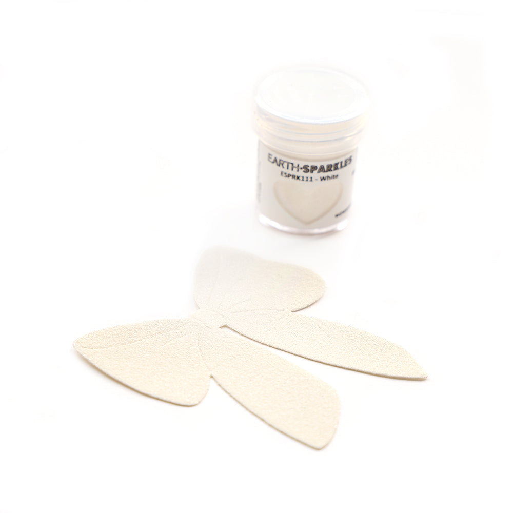 Ein kleines Döschen mit der Aufschrift WOW Embossing Powder steht neben vier hellen, blütenförmigen Ausschnitten auf weißem Hintergrund, in denen pflanzliche Glitzerflocken für einen Hauch von biologisch abbaubarem, umweltfreundlichem Bio Glitter sorgen.