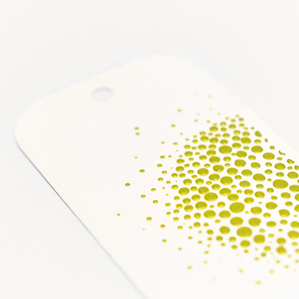 Der weiße Anhänger von Crafters Workshop mit abgerundeten Ecken ist mit gelb-grünen Punkten in verschiedenen Größen versehen - ideal, um Ihre Mixed-Media-Projekte mit Stencil Butter oder Modellierpaste zu ergänzen.