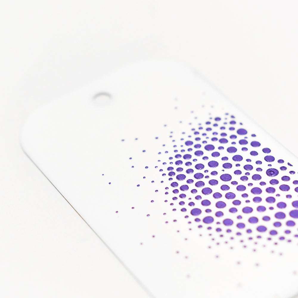 Weißer Anhänger mit Loch, mit einem Farbverlauf aus violetten Punkten in einem verblassenden Muster - ideal für Mixed-Media-Projekte oder in Kombination mit Stencil Butter für Textur. Von The Crafters Workshop.