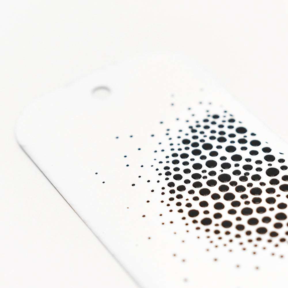 Diese weiße Karte von The Crafters Workshop zeigt ein schwarzes Punktmuster, das möglicherweise mit gemischten Medien wie Modellierpaste oder Schablonenbutter hergestellt wurde und ein kühnes Muster bildet, das zur unteren rechten Ecke hin größer wird.