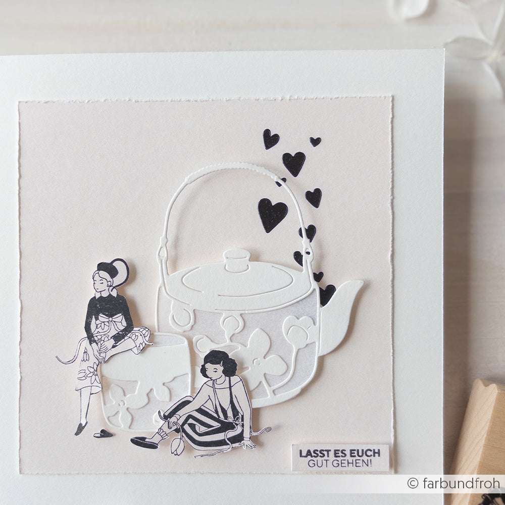 Das Mischtechnik-Papierbild von The Crafters Workshop zeigt eine Teekanne, zwei Frauen, eine Katze, schwebende Herzen und den Text "LASST ES EUCH GUT GEHEN!".