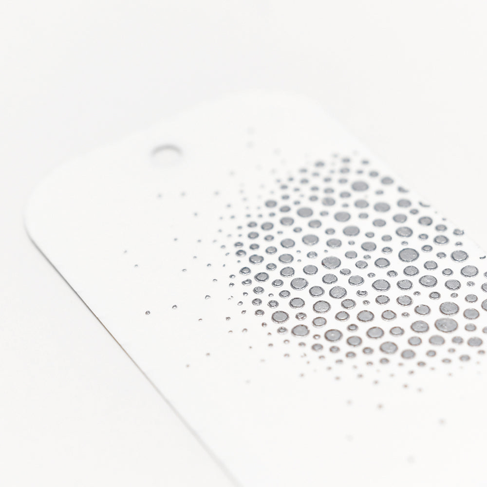 Weiße Karte von The Crafters Workshop mit einer Ansammlung kleiner grauer Punkte, die ein Farbverlaufsmuster bilden - ideal für Mixed-Media-Projekte. Oberes Loch gestanzt.