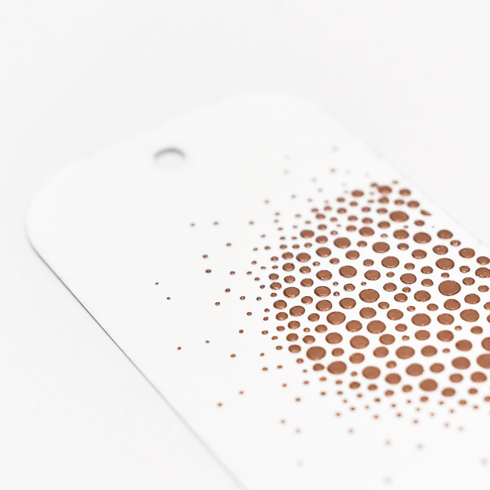 Weißer Anhänger von The Crafters Workshop mit einem Loch und braunen Punkten in einem kreisförmigen Farbverlauf - ideal für Mixed-Media-Projekte mit Stencil Butter oder Modellierpaste.