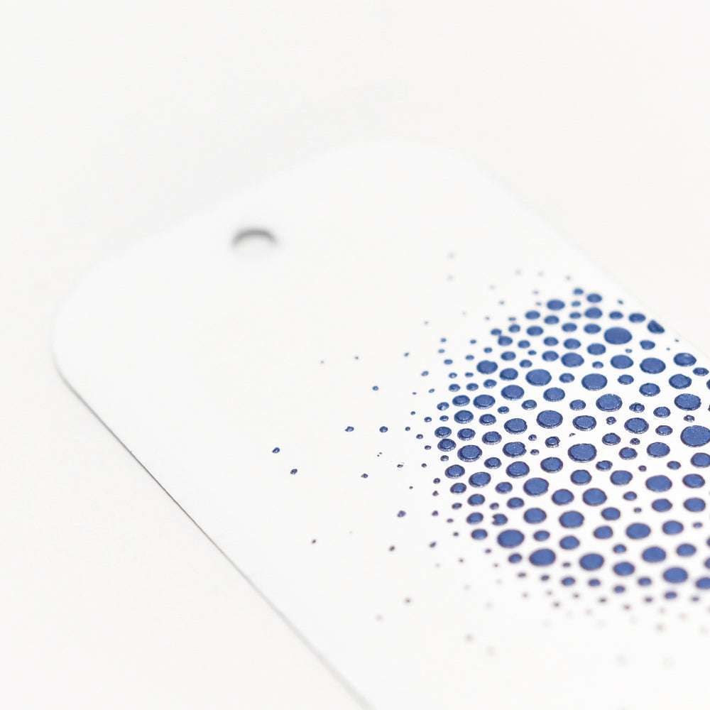 Weißer Anhänger mit einem Loch und einem blau gepunkteten kreisförmigen Muster von The Crafters Workshop, das nach außen hin verblasst - perfekt für einzigartige Mixed-Media-Projekte mit Modellierpaste oder Stencil Butter.