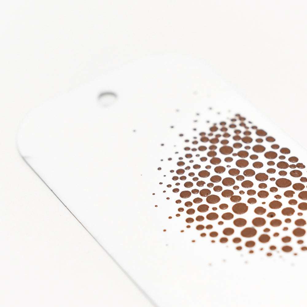 Ein weißer Anhänger von The Crafters Workshop mit einem braun gepunkteten Verlaufsmuster und einem Loch oben links, ideal für Mixed Media Projekte.