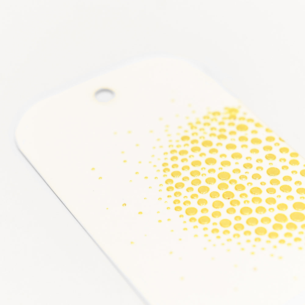 Ein weißer Anhänger von The Crafters Workshop mit abgerundeten Ecken, einem gelben Punktmuster und einem Loch oben - perfekt für Stencil Butter oder Mixed Media Techniken.
