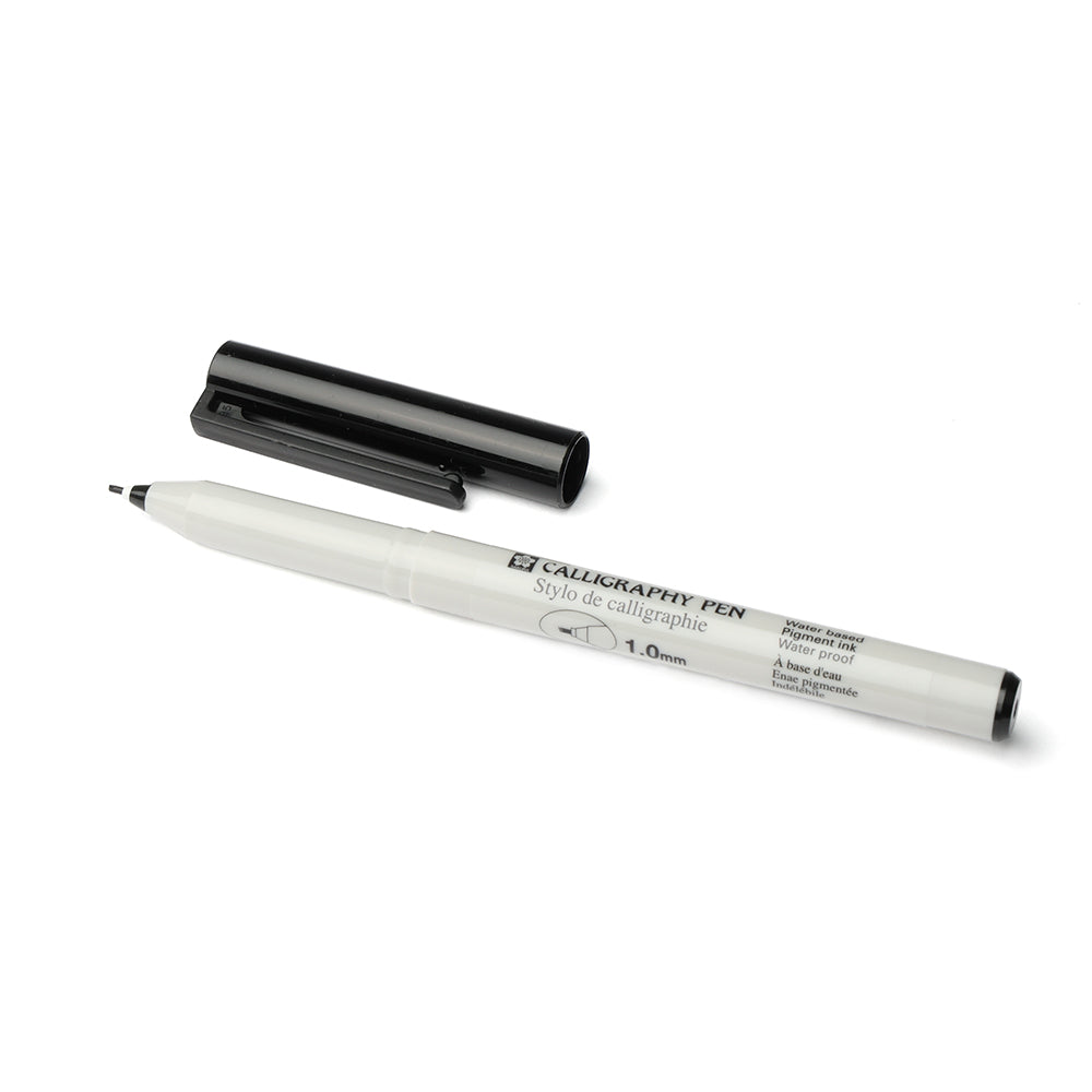 Ein Rico Design schwarzer Kalligraphie-Stift mit der Kappe entfernt und daneben auf einem weißen Hintergrund platziert, ideal zum kalligraphieren mit pigmentierter Tinte.