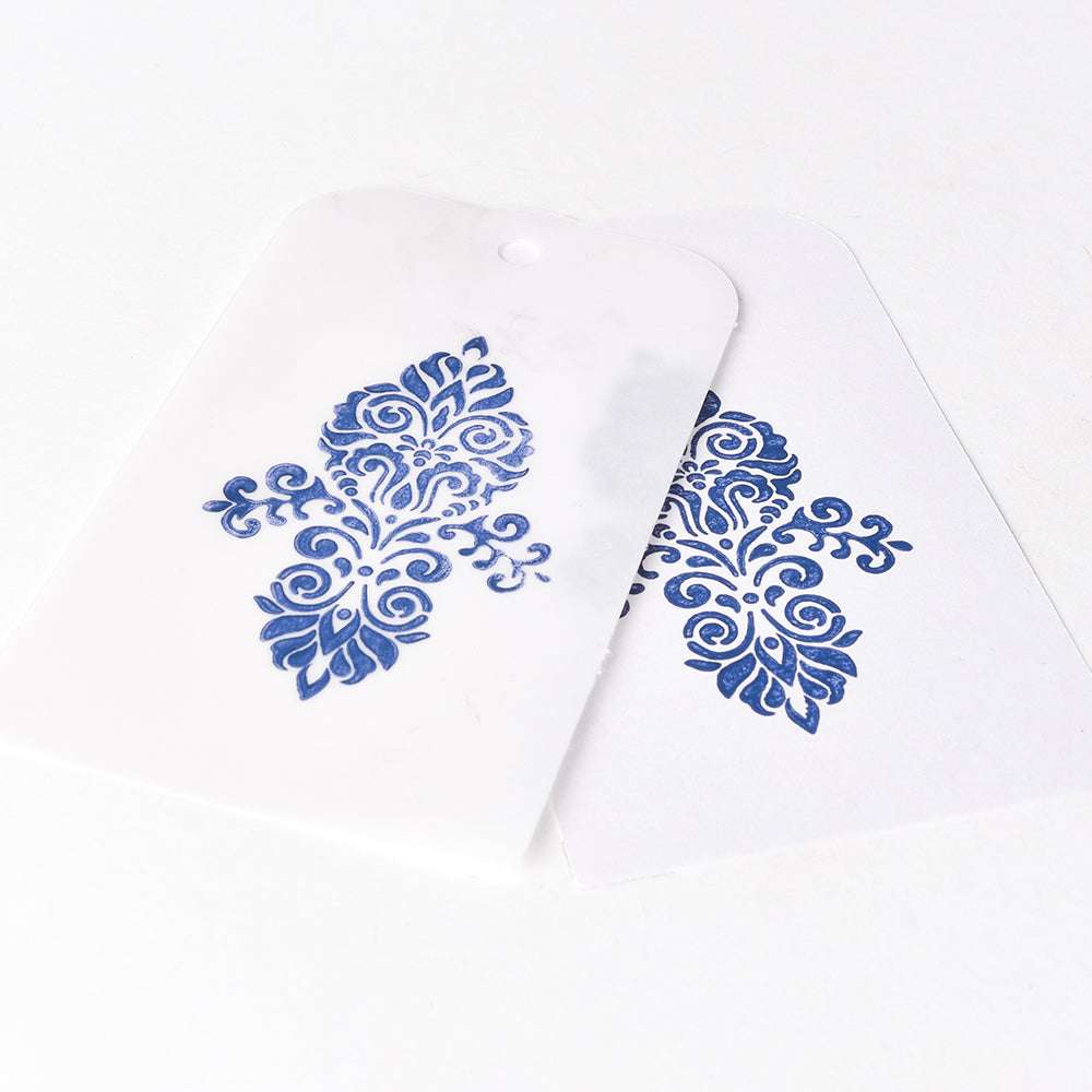 Zwei weiße Karten mit blauen Ornamenten, gestempelt mit Tsukineko Versa Magic Stempelkissen Pigment-Tinte, überlappen sich elegant auf einer weißen Fläche.