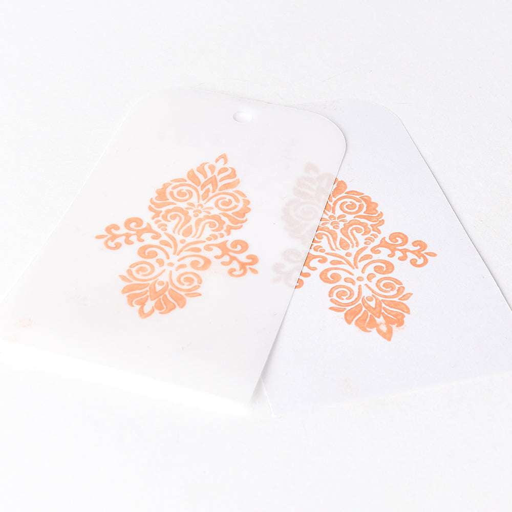 Zwei weiße Karten mit verschnörkelten orangefarbenen Mustern, erstellt mit Tsukineko Versa Magic Stempelkissen. Eine teilweise transparente Karte überlappt die andere und hebt die lebendigen Ergebnisse hervor, die mit reichhaltiger Pigmenttinte erzielt wurden.