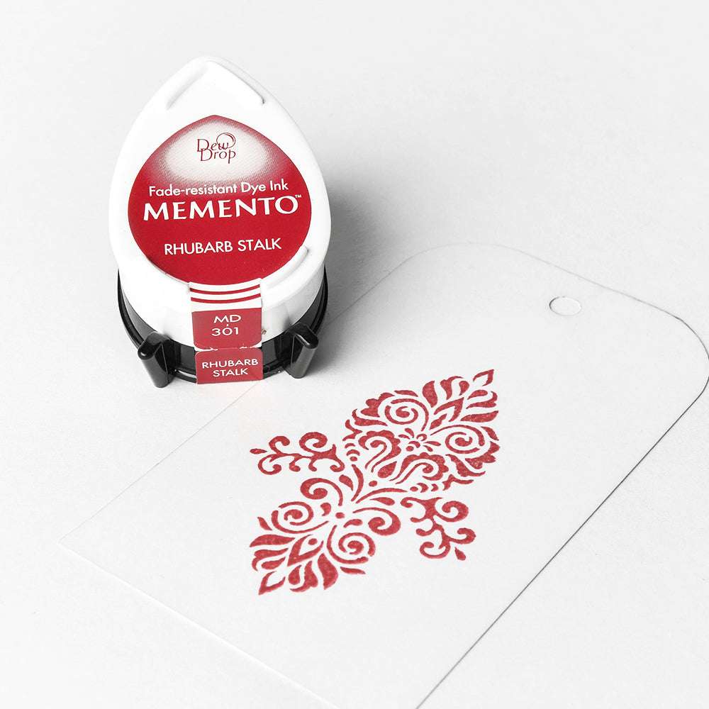 Tsukineko Red Memento Stempelkissen auf einem weißen Anhänger, der mit hochpigmentierter Tinte ein rotes, dekoratives Stempelmuster erzeugt.